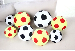 Detailed plush soccer pillows in various sizes and colors on a beige sofa