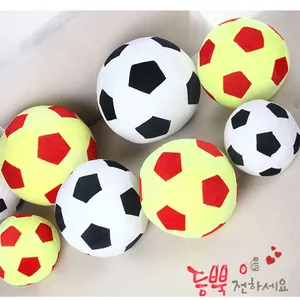 Detailed view of stacked soccer plush pillows in classic black, white and red, yellow colors
