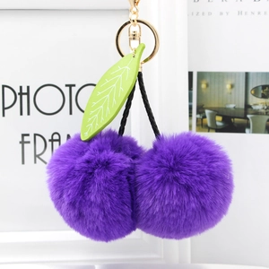 Detail of purple faux fur cherry keychain with green leaves and gold ring