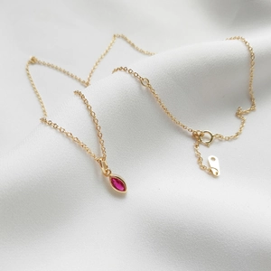 Macro shot of marquise-cut pink gemstone pendant on a gold chain with delicate lobster clasp