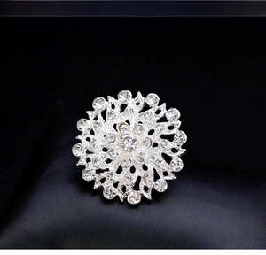 Detailed macro view of a silver floral brooch featuring radiant petals with clear rhinestones