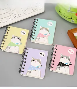 Detailed view of four A7 mini spiral notebooks with cute cat illustrations on a desk