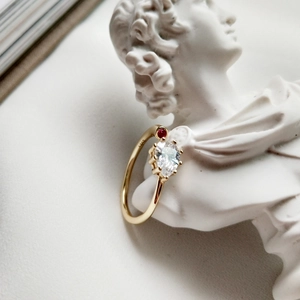Close-up of S925 sterling silver gold ring with clear zircon and red gemstone detail