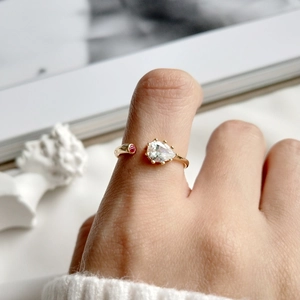Detail of adjustable gold ring with teardrop zircon and red stone on hand