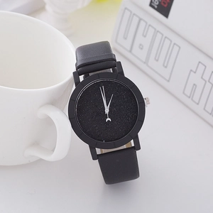 Minimalist black starry dial watch with leather strap displayed on office desk background