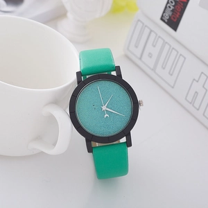Minimalist quartz watch featuring a grainy green dial against a white ceramic cup background