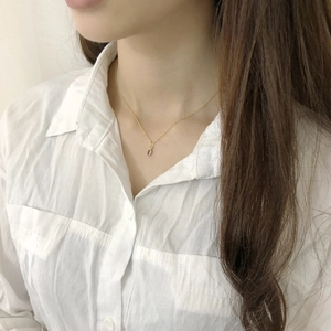 Close-up of minimalist gold necklace with red oval gemstone pendant on model