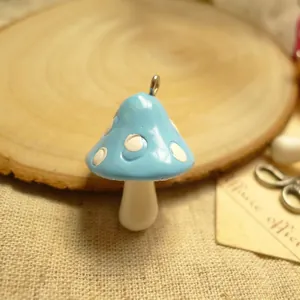 Detail of blue resin mushroom charm with white dots and metal ring for DIY jewelry