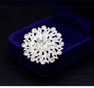 Detailed close-up of a silver hollow sunflower brooch with rhinestones in a velvet box