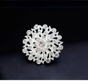 Macro shot of silver radial brooch with sparkling rhinestones on black leather texture