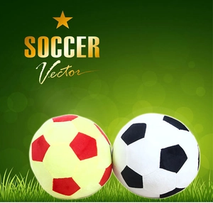 Close-up of yellow-red and black-white plush soccer pillows on a green background