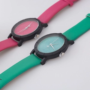 Detail of minimalist quartz watches featuring matte black dials with teal and rose straps