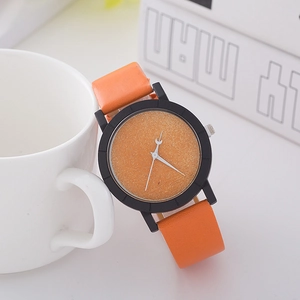 Close-up of orange quartz watch with leather strap displayed next to a white ceramic mug