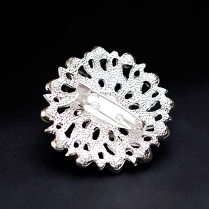 Back view of silver hollow round brooch pin with secure metal safety clasp on leather