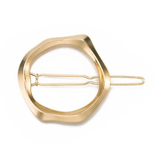 Macro view of golden geometric irregular round hair clip with twisted metal texture