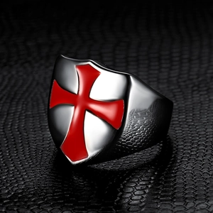 Macro detail of silver shield ring with red enamel cross inlay on dark background