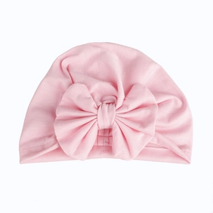 Detailed view of pink cotton baby turban hat with a large bow on white background