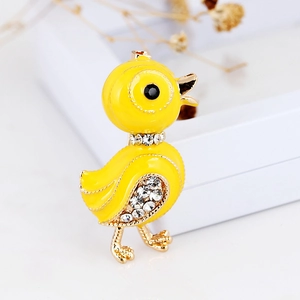 Macro detail of a yellow enamel duck brooch with sparkling rhinestones and golden trim