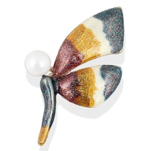 Detailed close-up of dragonfly brooch with colorful enamel wings and a white pearl head