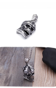 Detailed macro view of vintage pirate skull pendant in steel on textured wood backdrop