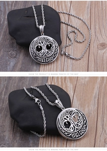 Detailed view of silver tree of life pendant with Celtic knot on dark stone surface