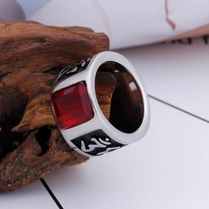 Vintage stainless steel ring with red rectangular gemstone and OM symbol on wood