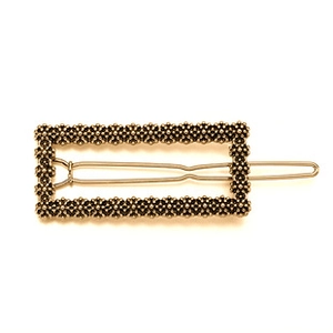 Close-up of a vintage gold alloy rectangular hair clip with fine beaded metal texture