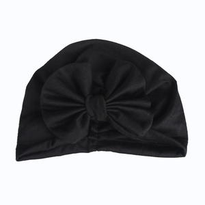 Detail of baby cotton beanie featuring a classic black knit fabric and oversized bow