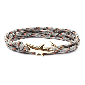 Detailed macro view of woven paracord rope and golden shark anchor clasp on nautical bracelet
