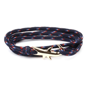 Macro detail of navy woven nautical bracelet with a gold shark anchor clasp closure