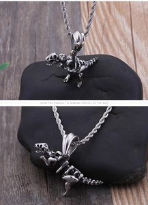Detailed close-up of a silver stainless steel dinosaur skeleton pendant with rope chain