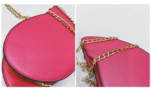 Close-up of pink heart-shaped leather crossbody bag featuring a golden chain strap