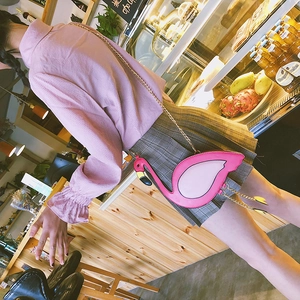 Chic pink flamingo crossbody bag with golden chain strap shown on model in cafe