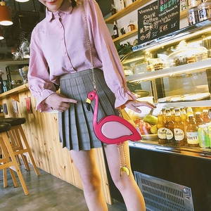 Detail of pink flamingo crossbody bag with gold chain strap in a cozy cafe setting