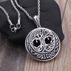 Silver Tree of Life pendant necklace on black stone over a rustic wood background