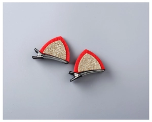 Detail of red and gold sequin cat ear hair clip with black alligator clamp on gray background