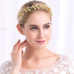 Detail eines goldenen Vintage-Haarreifs mit Strasssteinen an einem Modell bei weichem Licht
