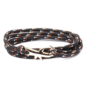 Detailed close-up of a woven nautical bracelet with a gold shark-shaped anchor clasp