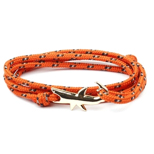 Detail of orange woven nautical rope bracelet with a gold shark-shaped anchor clasp