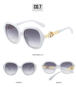 Detail view of oval sunglasses with gold metal logo temple and white acetate frame