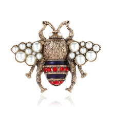 Macro detail of vintage gold bee brooch with white pearls and blue enamel inlay