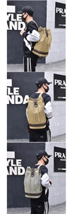 Detail of canvas bucket backpack with drawstring closure and leather accents in khaki and green
