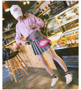 Pink flamingo crossbody bag with gold chain strap shown in a stylish cafe setting