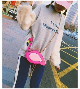 Close-up of pink flamingo shaped crossbody bag with gold chain strap on a model