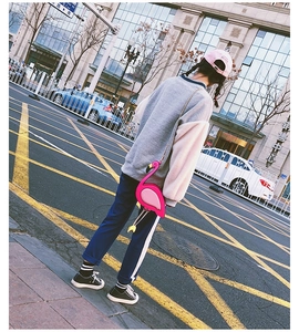 Street style shot of a creative pink flamingo-shaped crossbody bag with a metal chain