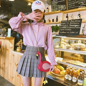 Detailed shot of a 3D flamingo crossbody bag paired with a pink shirt and plaid skirt