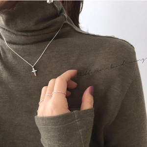 Detail shot of a minimalist S925 sterling silver hollow woven ring and a cross pendant