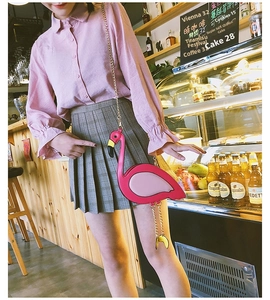 Detailed view of pink flamingo crossbody bag with golden chain strap in a cafe setting