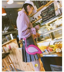 Pink flamingo shaped crossbody bag with gold chain strap shown in a cozy cafe setting