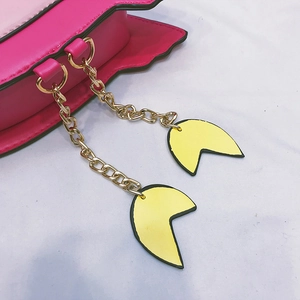 Detail of pink flamingo bag featuring gold chain tassels and yellow Pac-Man decorations